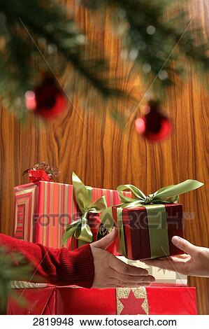 Stock Photo - People's hands holding Christmas present . Fotosearch
