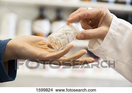 Pharmacist giving pill bottle to customer View Large Photo Image Picture - Pharmacist giving pill bottle to customer . Fotosearch