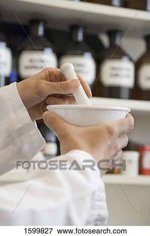 Stock Photo - Pharmacist in pharmacy using mortar and pestle . Fotosearch