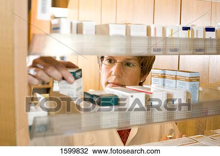 Pharmacist looking at medicine in pharmacy View Large Photo Image Stock Image - Pharmacist looking at medicine in pharmacy . Fotosearch