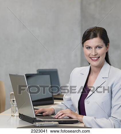 Stock Image - Portrait of businesswoman using laptop and smiling . Fotosearch