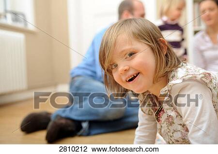 Stock Image - Portrait of girl smiling with her family in background . Fotosearch