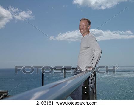 Portrait of man leaning against railing and smiling View Large Photo Image Stock Image - Portrait of man leaning against railing and smiling . Fotosearch