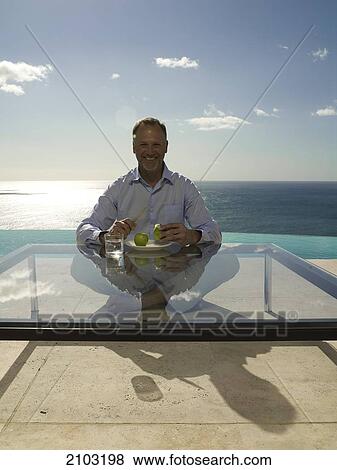 Portrait of man peeling apple and smiling at poolside View Large Photo Image Stock Photo - Portrait of man peeling apple and smiling at poolside . Fotosearch