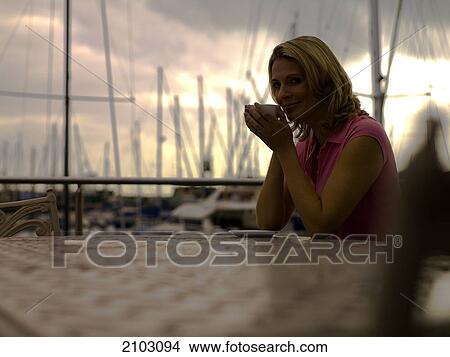 Portrait of woman drinking tea at table View Large Photo Image Picture - Portrait of woman drinking tea at table . Fotosearch
