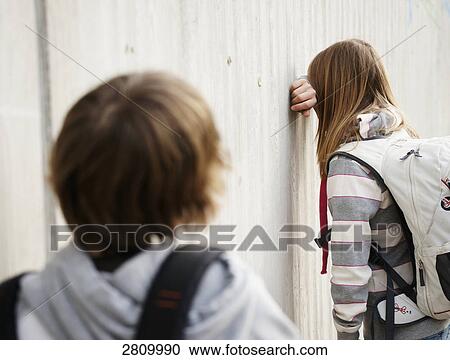 Primary school student covering her face against wall View Large Photo Image Stock Image - Primary school student covering her face against wall . Fotosearch