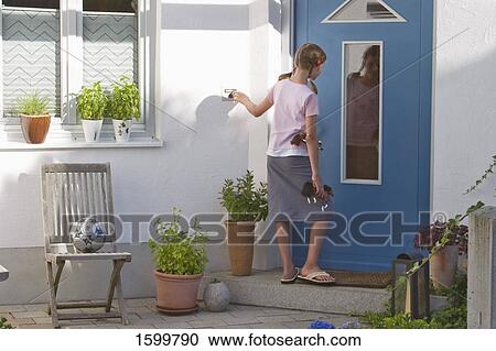Stock Image - Rear view of girl ringing doorbell . Fotosearch