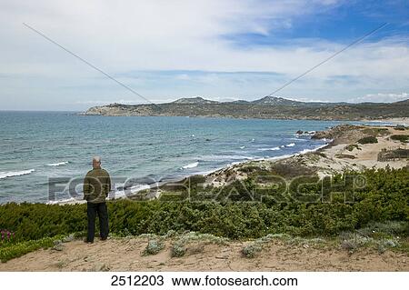 Stock Image - Rear view of man standing at coast . Fotosearch