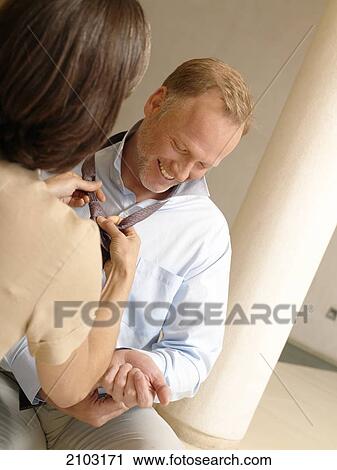 Rear view of woman tying her husband's tie View Large Photo Image Stock Image - Rear view of woman tying her husband's tie . Fotosearch