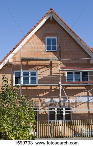 Stock Image - Scaffoldings on under construction house . Fotosearch