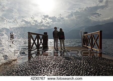 Senior couple at sunset looking on water, Italy, Malcesine View Large Photo Image Stock Photo - Senior couple at sunset looking on water, Italy, Malcesine . Fotosearch
