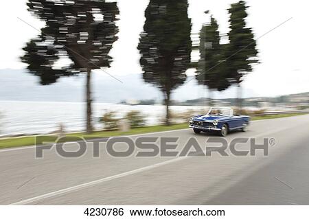 Senior couple driving convertible on coastal road, Italy, Gardasee East Bay View Large Photo Image Stock Photograph - Senior couple driving convertible on coastal road, Italy, Gardasee East Bay . Fotosearch