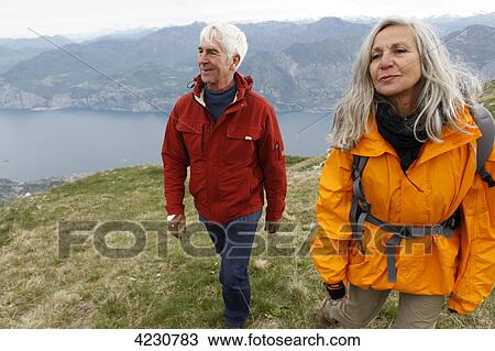 Stock Image - Senior couple hiking in mountain range, Italy, Monte Baldo . Fotosearch
