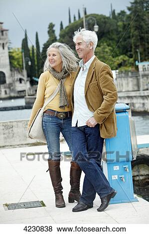 Stock Photo - Senior couple standing outdoors, Italy, Gardone Riviera . Fotosearch
