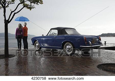 Senior couple with vintage car and umbrella at pier, Italy, Gargnano View Large Photo Image Stock Photo - Senior couple with vintage car and umbrella at pier, Italy, Gargnano . Fotosearch