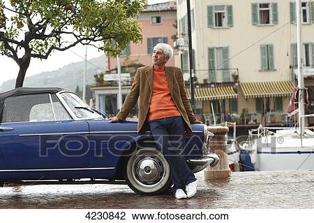 Senior man leaning against vintage car at harbor, Italy, Gargnano, Gardasee View Large Photo Image Stock Image - Senior man leaning against vintage car at harbor, Italy, Gargnano, Gardasee . Fotosearch