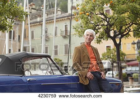 Senior man leaning against vintage car at harbor, Italy, Linfano View Large Photo Image Stock Photo - Senior man leaning against vintage car at harbor, Italy, Linfano . Fotosearch