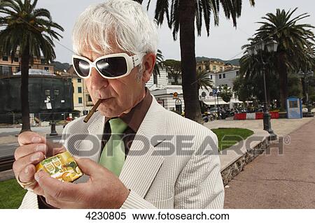 Stock Photography - Senior man lighting a cigarillo, Italy, Rapallo . Fotosearch