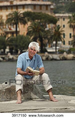 Stock Image - Senior man reading a book, North Italy, Europe, Rapallo . Fotosearch