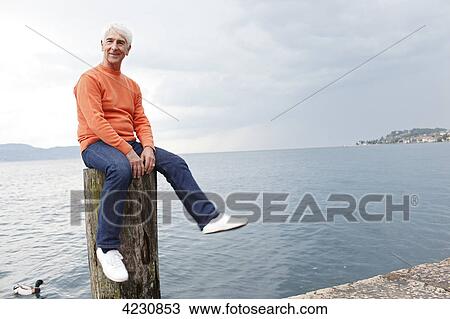 Senior man sitting on groyne by the water, Italy, Gargnano View Large Photo Image Stock Image - Senior man sitting on groyne by the water, Italy, Gargnano . Fotosearch