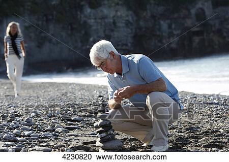 Senior man stacking stones on beach, Italy, Sori View Large Photo Image Stock Image - Senior man stacking stones on beach, Italy, Sori . Fotosearch