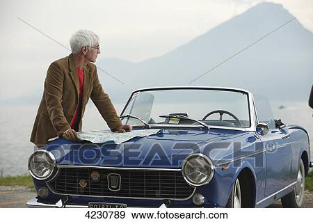Stock Photo - Senior man with convertible at the ocean, Italy, Gardasee East bay . Fotosearch