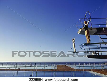 Side profile of couple standing on diving board View Large Photo Image Picture - Side profile of couple standing on diving board . Fotosearch