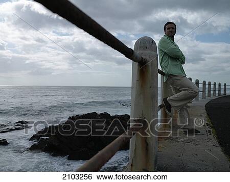 Side profile of man leaning against railing at coast View Large Photo Image Stock Photograph - Side profile of man leaning against railing at coast . Fotosearch