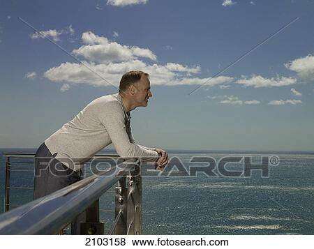 Stock Photo - Side profile of man leaning on railing and smiling . Fotosearch