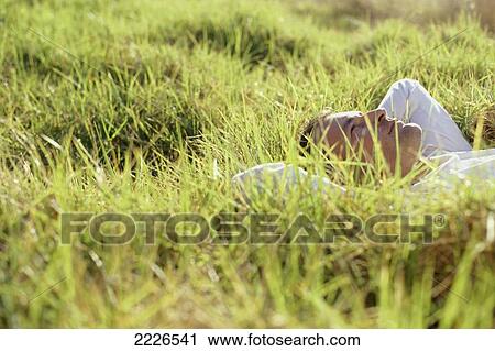 Side profile of man lying on grass View Large Photo Image Stock Image - Side profile of man lying on grass . Fotosearch