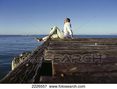 Side profile of man sitting on pier View Large Photo Image Stock Photo - Side profile of man sitting on pier . Fotosearch