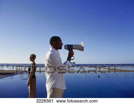 Side profile of man using megaphone with woman standing in background View Large Photo Image Stock Image - Side profile of man using megaphone with woman standing in background . Fotosearch