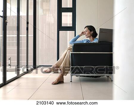 Side profile of woman sitting with laptop in armchair and looking through window View Large Photo Image Stock Image - Side profile of woman sitting with laptop in armchair and looking through window . Fotosearch