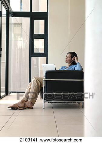 Side profile of woman sitting with laptop in armchair and looking through window View Large Photo Image Stock Image - Side profile of woman sitting with laptop in armchair and looking through window . Fotosearch