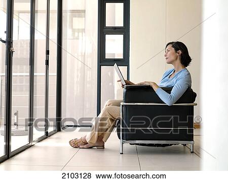 Side profile of woman using laptop on couch View Large Photo Image Stock Photo - Side profile of woman using laptop on couch . Fotosearch