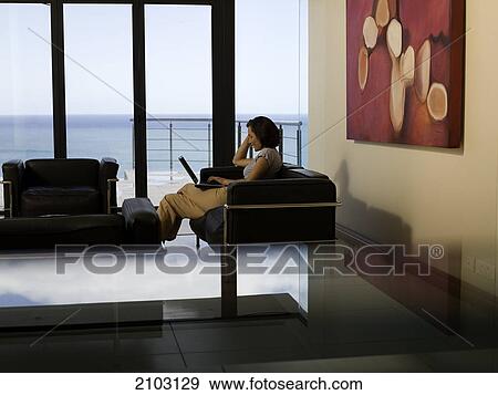 Side profile of woman using laptop on couch View Large Photo Image Stock Photo - Side profile of woman using laptop on couch . Fotosearch