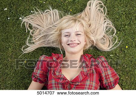 Stock Photo - Smiling blond woman lying in grass . Fotosearch
