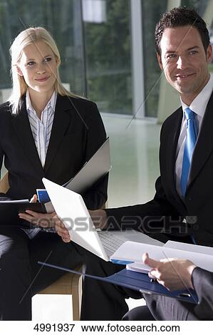 Stock Photo - Smiling businesspeople with laptop and documents . Fotosearch
