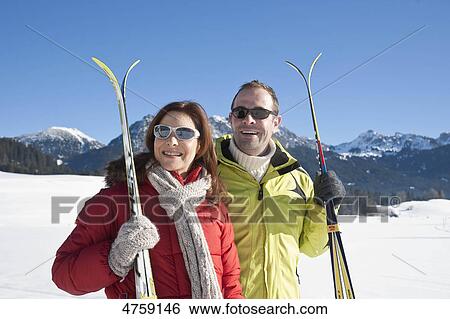 Smiling couple with skis in winter landscape, Tannheimer Tal, Tyrol, Austria View Large Photo Image Stock Photograph - Smiling couple with skis in winter landscape, Tannheimer Tal, Tyrol, Austria . Fotosearch