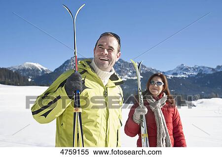 Stock Photography - Smiling couple with skis in winter landscape, Tannheimer Tal, Tyrol, Austria . Fotosearch