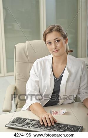 Smiling doctor's assistant at desk in medical practice View Large Photo Image Stock Photograph - Smiling doctor's assistant at desk in medical practice . Fotosearch