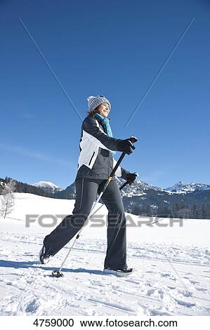 Stock Image - Smiling woman nordic walking in winter landscape, Tannheimer Tal, Tyrol, Austria . Fotosearch