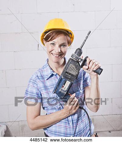 Smiling woman with helmet and drill View Large Photo Image Stock Image - Smiling woman with helmet and drill . Fotosearch