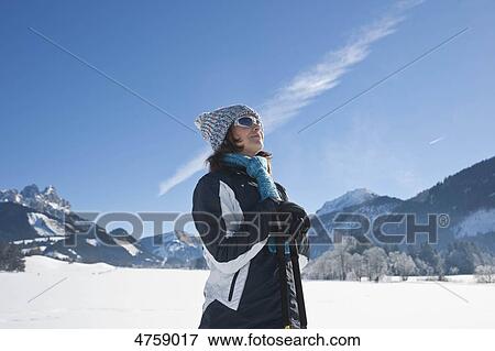 Stock Photo - Smiling woman with nordic walking poles in winter landscape, Tannheimer Tal, Tyrol, Austria . Fotosearch