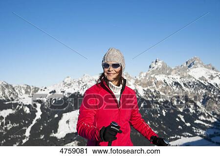 Stock Image - Smiling woman with ski poles in winter landscape, Tannheimer Tal, Tyrol, Austria . Fotosearch