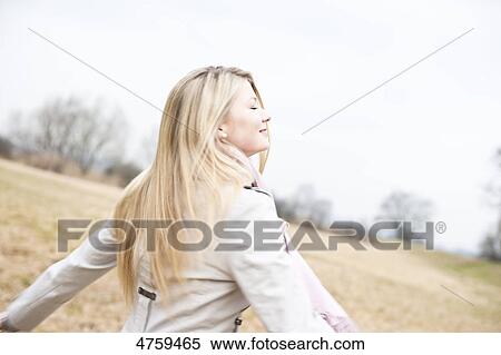 Stock Photography - Smiling young woman in field . Fotosearch