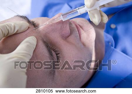 Surgeon injecting into forehead of patient View Large Photo Image Stock Photography - Surgeon injecting into forehead of patient . Fotosearch