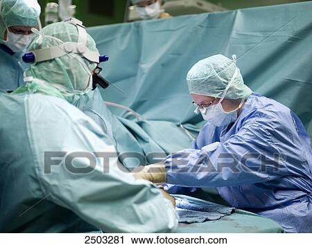 Stock Image - Surgeons performing operation in operating room . Fotosearch
