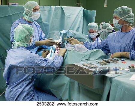 Stock Image - Surgeons performing operation in operating room . Fotosearch