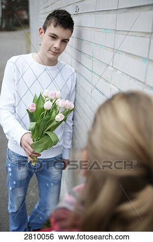 Teenage boy giving flowers to his girlfriends View Large Photo Image Stock Photograph - Teenage boy giving flowers to his girlfriends . Fotosearch